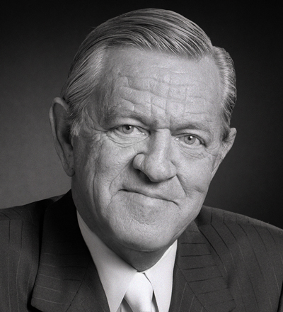 Bill-Daniels-400x440px Bill Daniels wearing a suit and tie smiling and looking at the camera