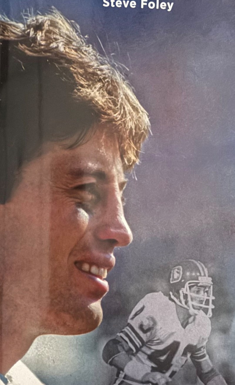 Profile of a smiling man with a faint image of a football player in the background.