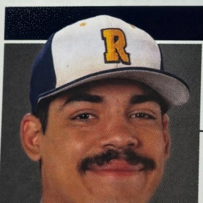Person wearing a baseball cap with a yellow 'R' on the front, smiling.