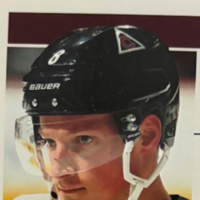 Hockey player wearing helmet and visor, looking focused.