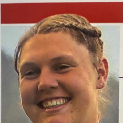 Smiling person with braided hair and earrings.