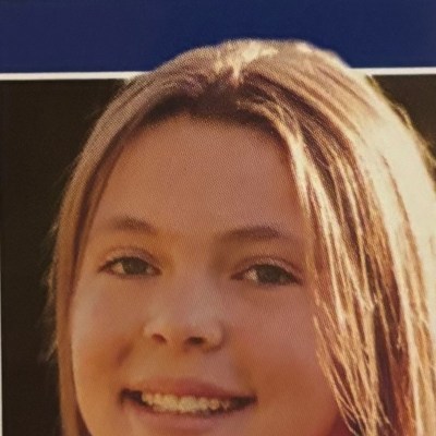 Smiling individual with long light brown hair in a portrait.