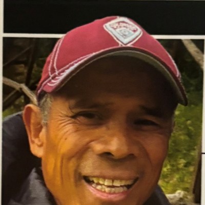 Man smiling, wearing a maroon cap and blue jacket.